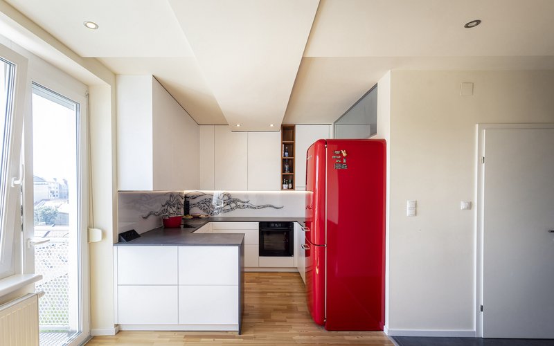 Moderne weisse Kueche mit rotem Kuehlschrank.